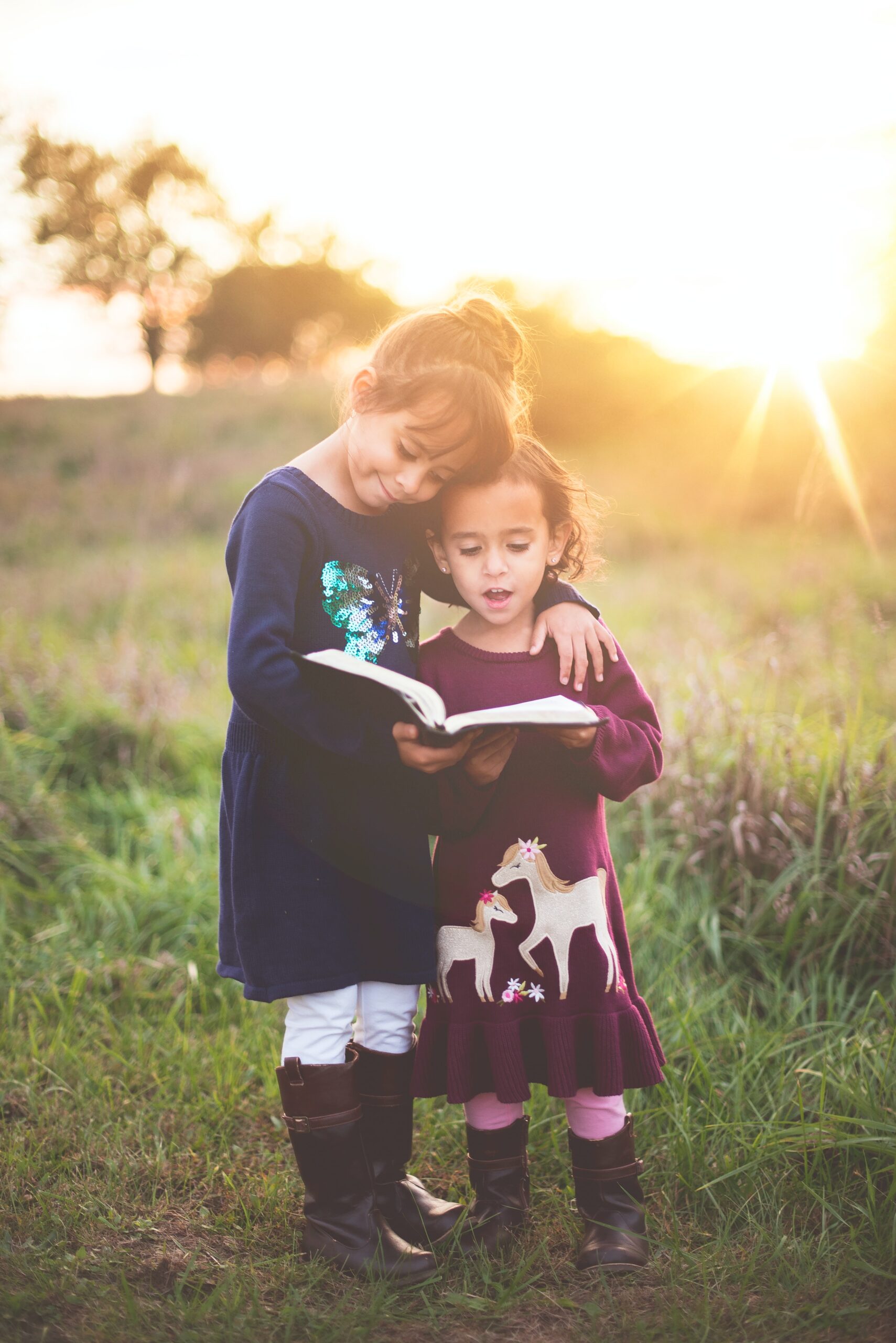 Sisters reading to each other in field by Ben White on Unsplash