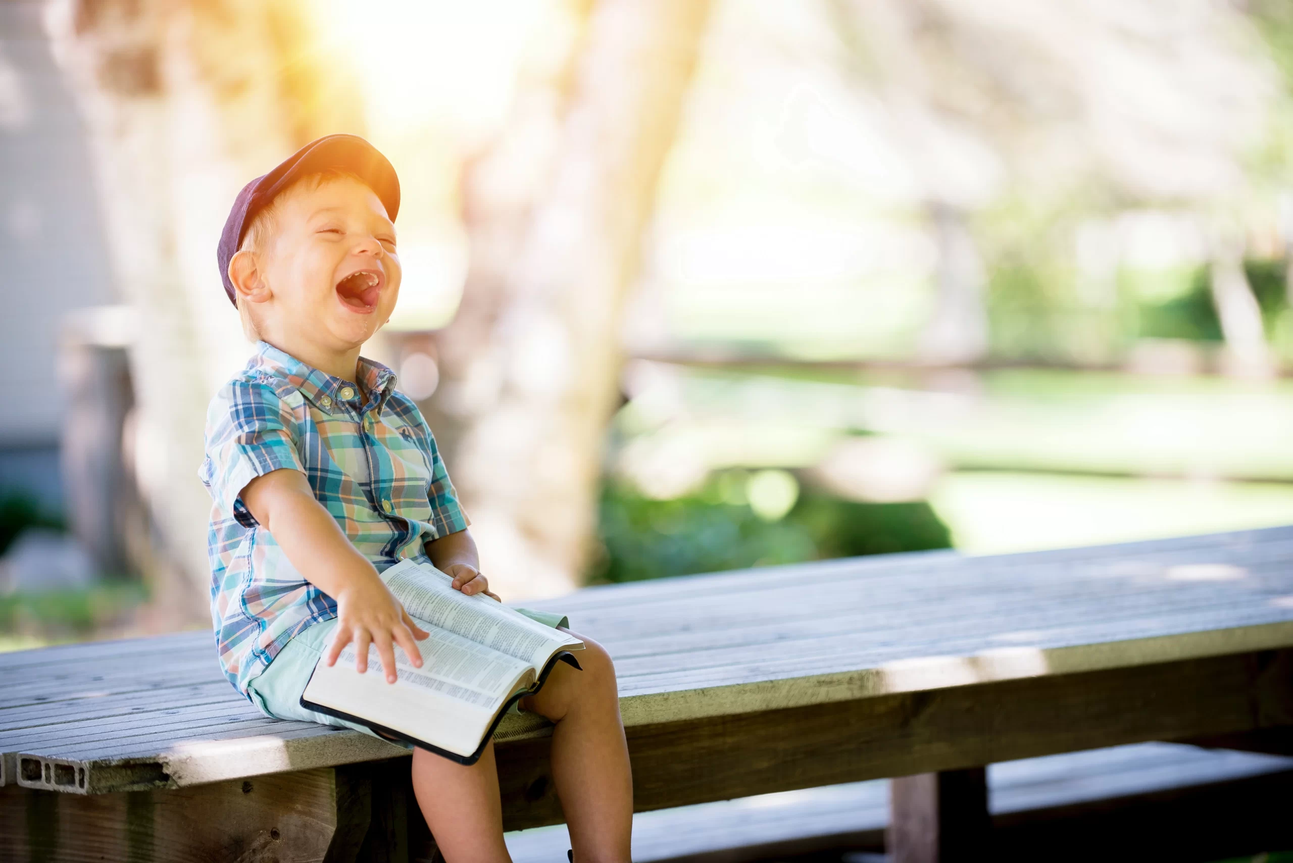 ben-white-young boy sitting on dock exclaiming while reading the bible -unsplash